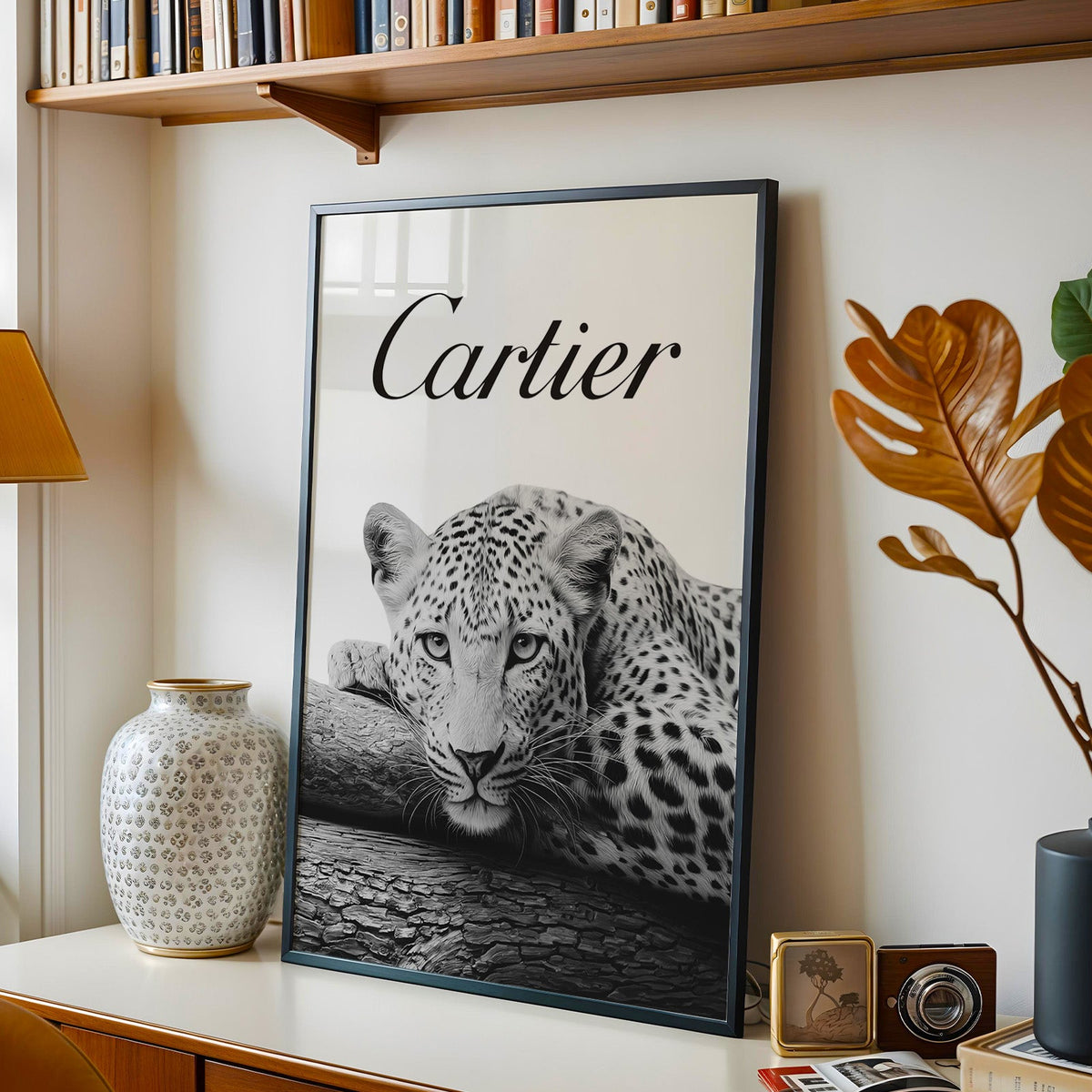 Leopard resting chin on cracked log with script wordmark in a black frame on a console under a bookshelf