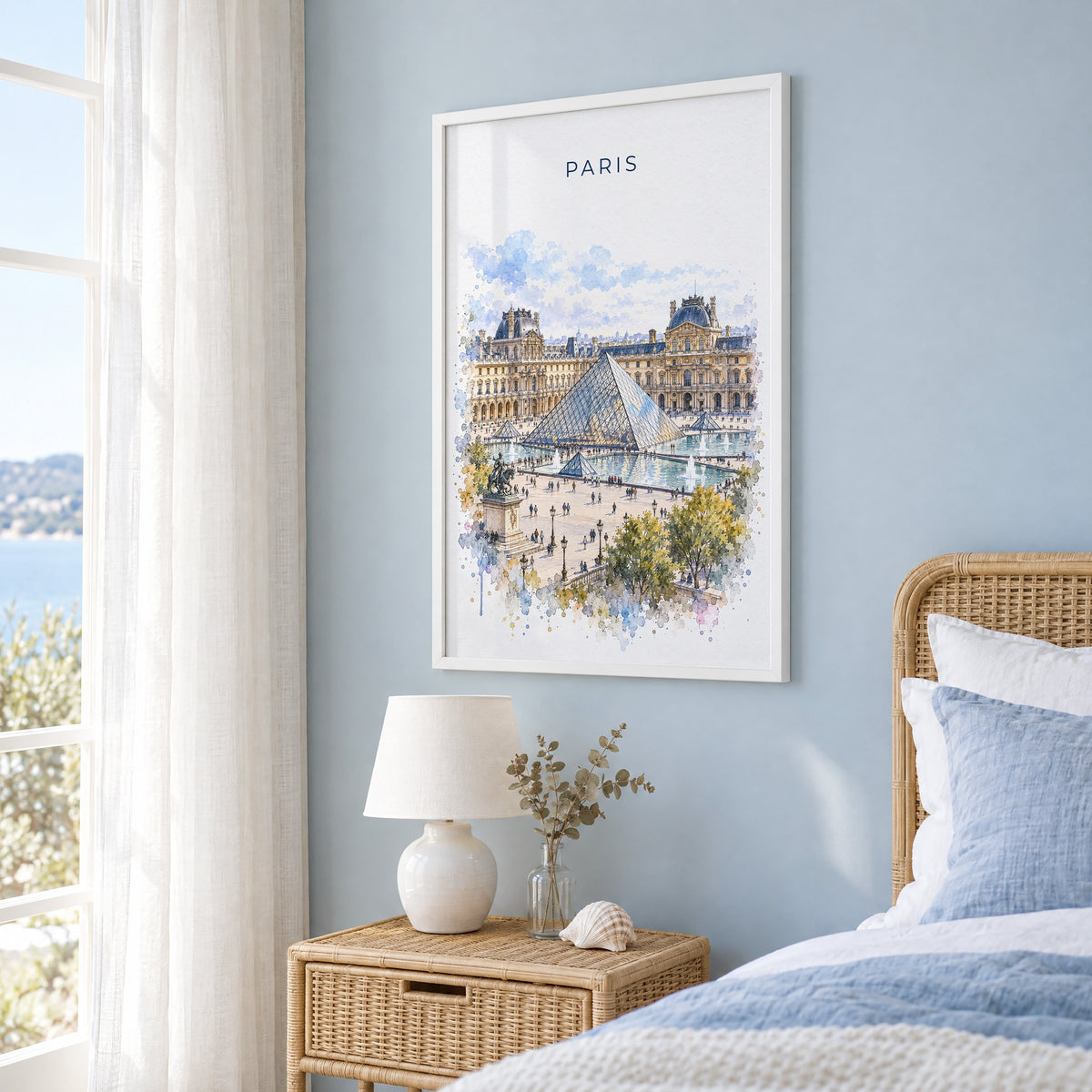 Louvre watercolor print in a white frame on a pale blue wall beside a rattan bed in a coastal bedroom