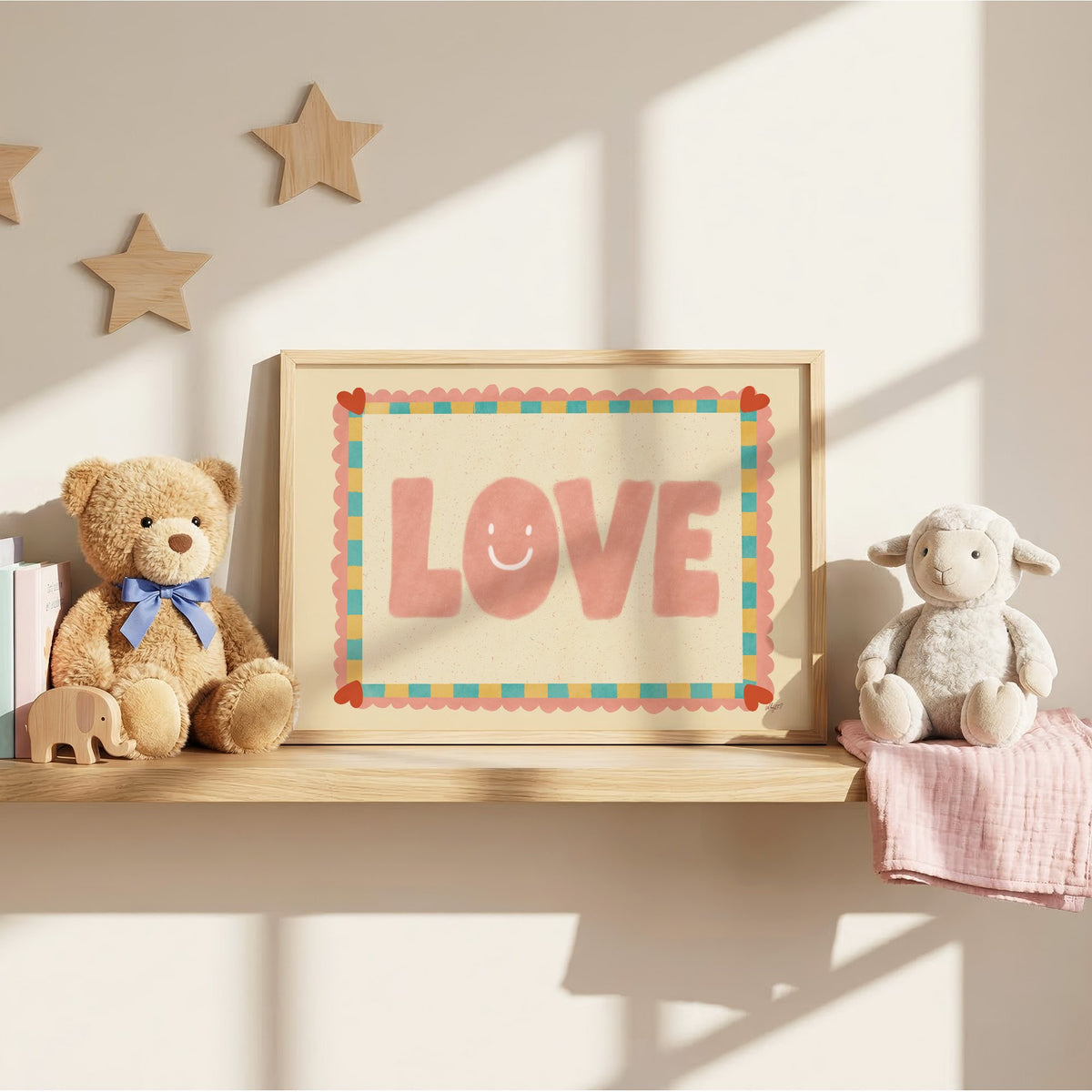 Love smiley face checkered border nursery print in an oak frame on a wall shelf between a teddy bear and a toy lamb