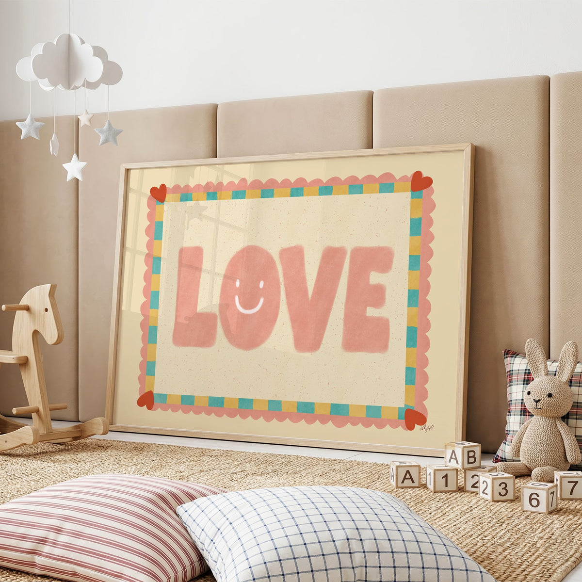 Love smiley face checkered border nursery print in an oak frame on a padded wall by a wooden rocking horse