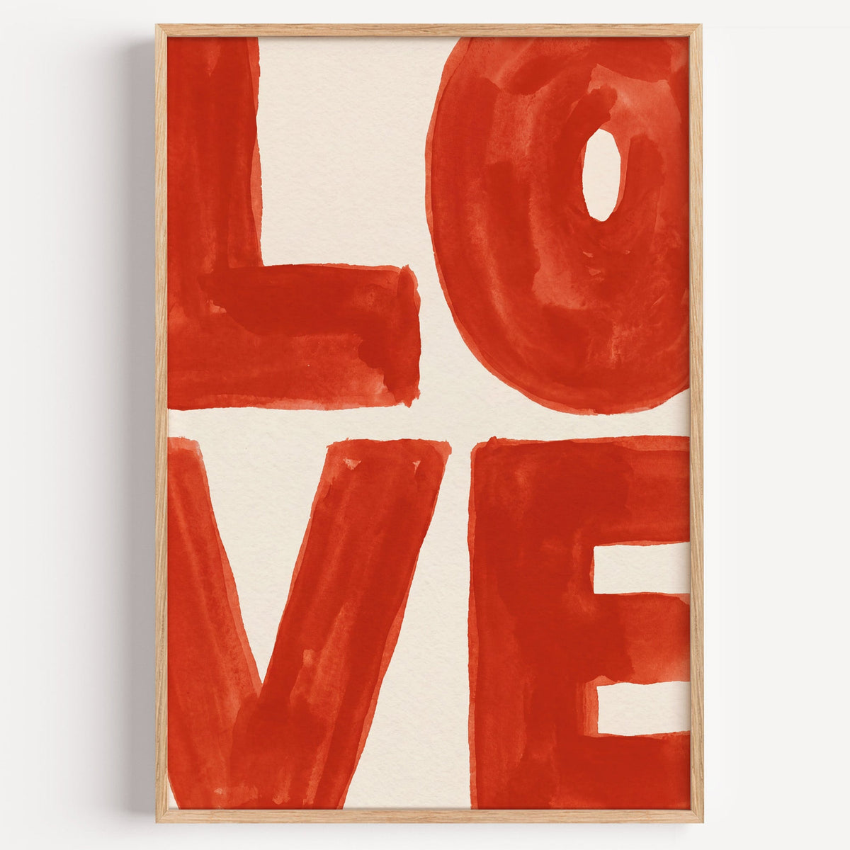 LOVE watercolor letters print in a light oak frame on a plain white wall