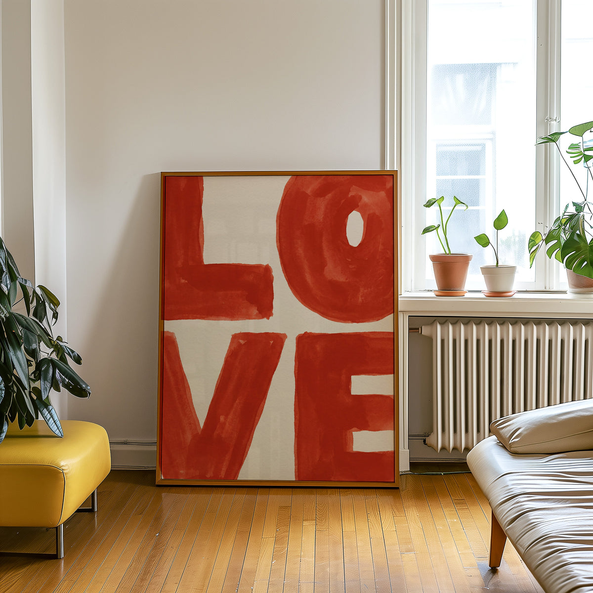 Red orange word art print in an oak frame leaning beside a yellow leather bench