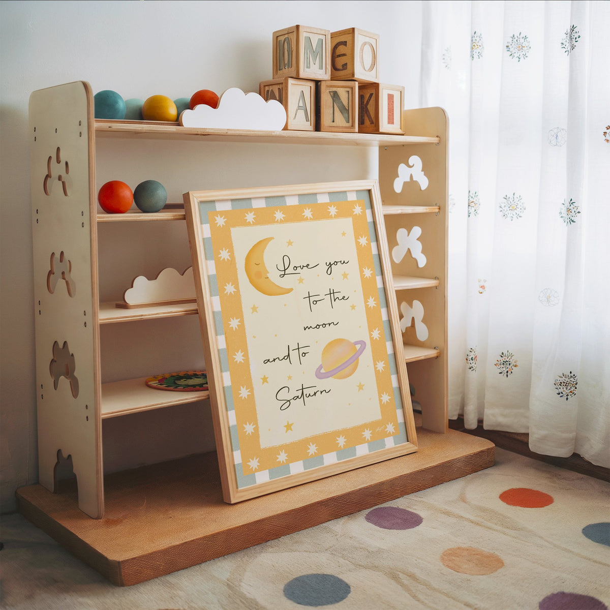 Love you moon and saturn nursery print in an oak frame leaning on a toy shelf with wooden letter blocks