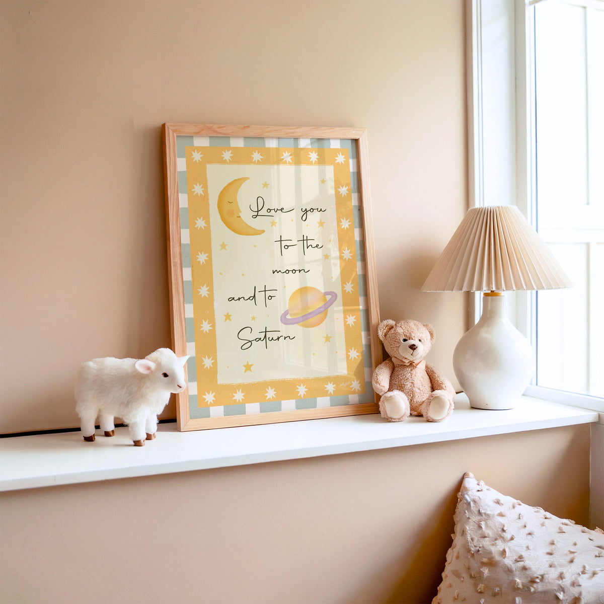 Love you moon and saturn nursery print in an oak frame on a window ledge with a toy lamb and teddy