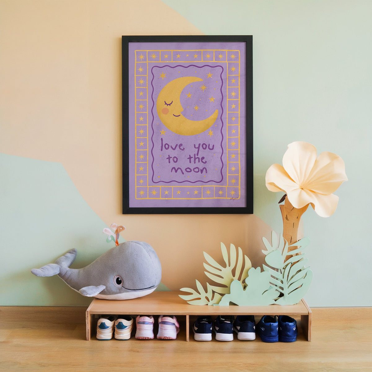 Lavender love you to the moon nursery print in a black frame on a mint and peach wall above a whale plush