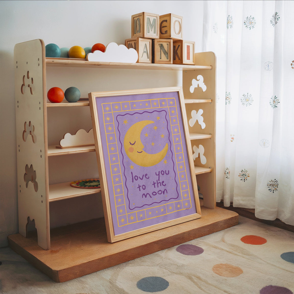 Lavender love you to the moon nursery print in an oak frame leaning on a toy shelf with wooden letter blocks