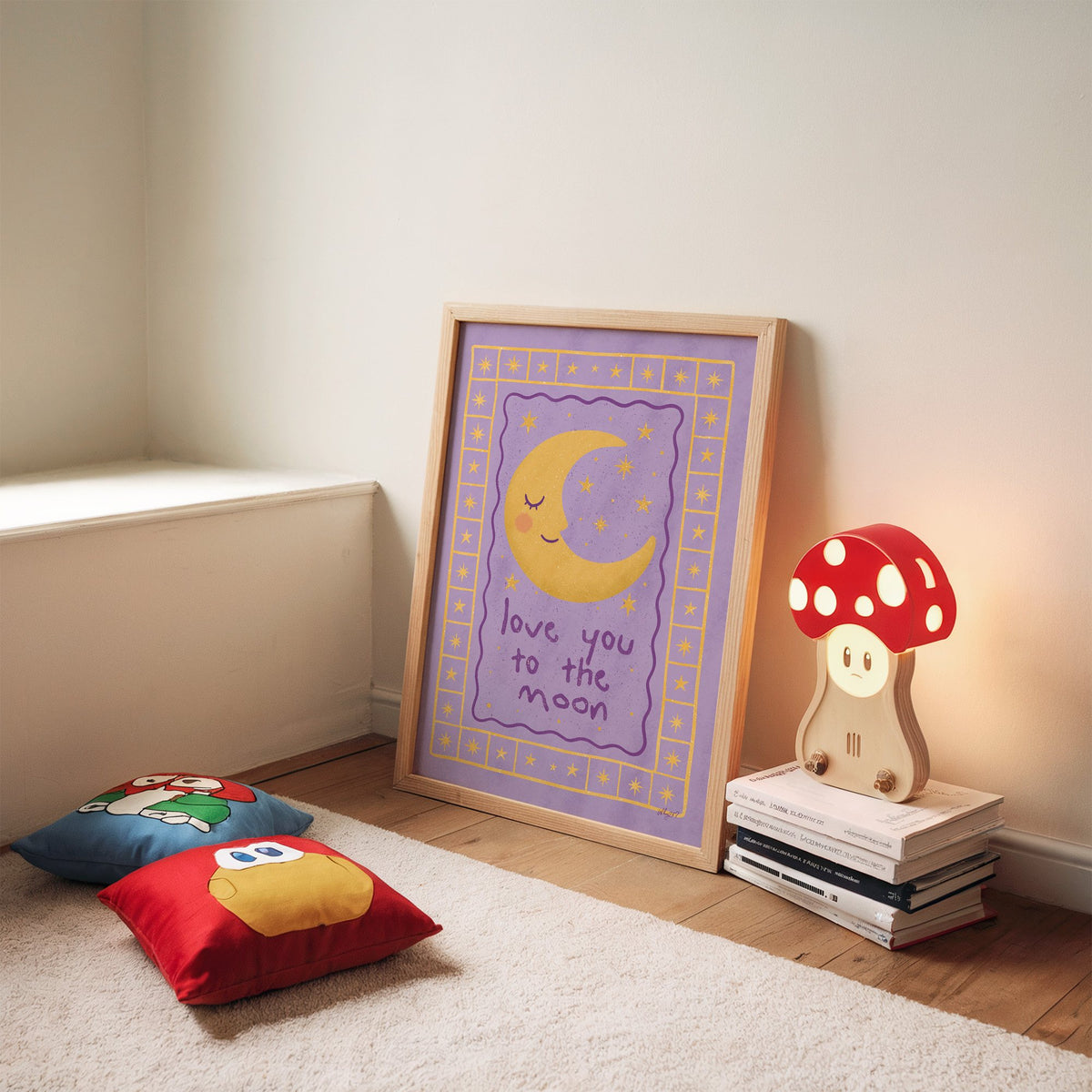 Lavender love you to the moon nursery print in an oak frame leaning on a rug beside a mushroom lamp and floor cushions