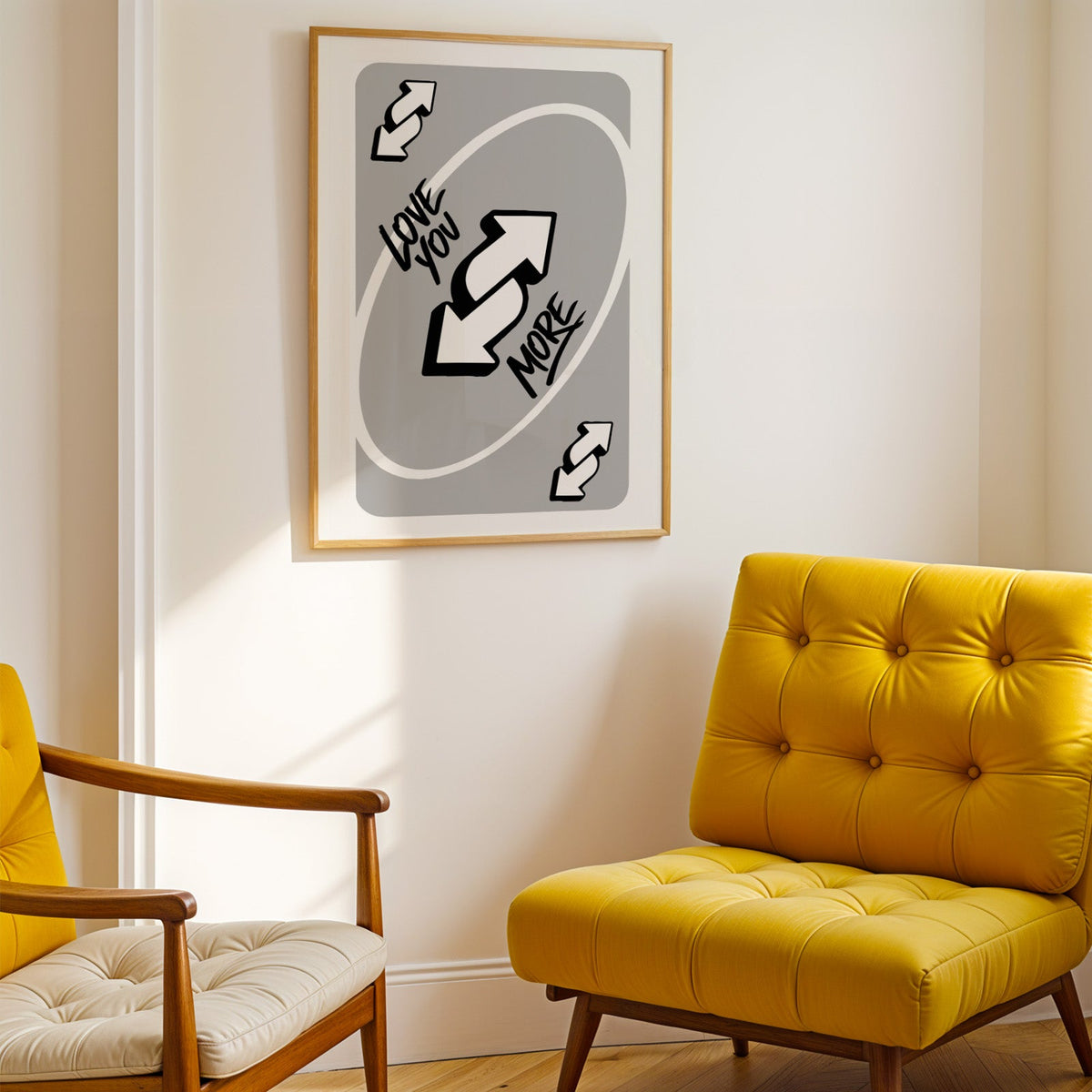 Love you more reverse arrows card print shown in a gold frame above a mustard yellow tufted armchair