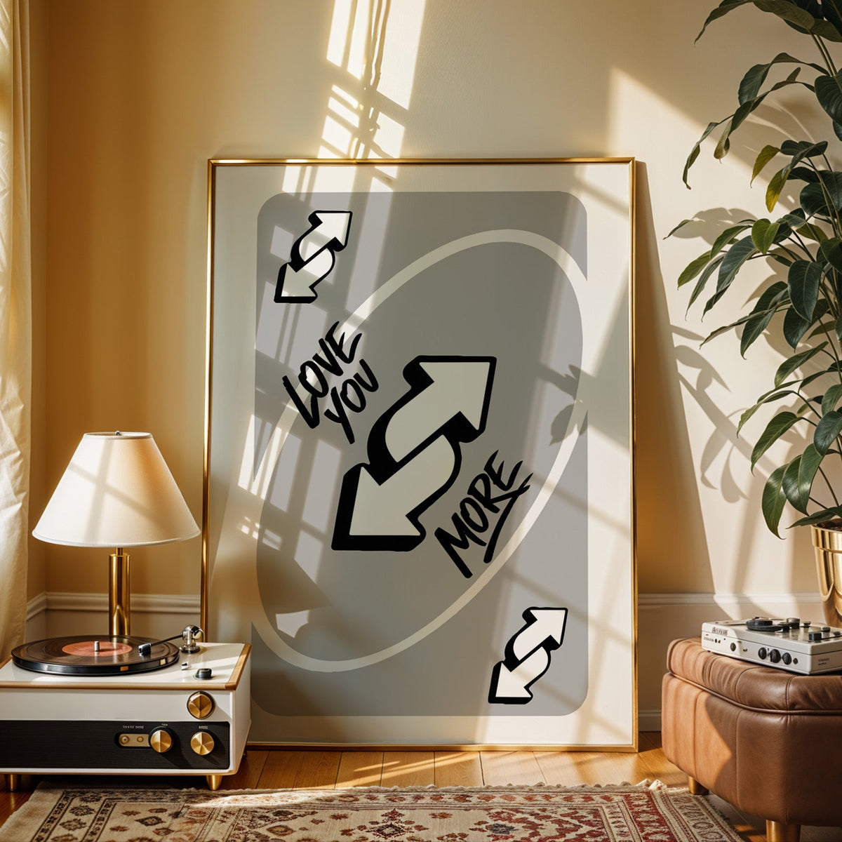 Love you more reverse arrows card print shown in a gold frame beside a record player and table lamp