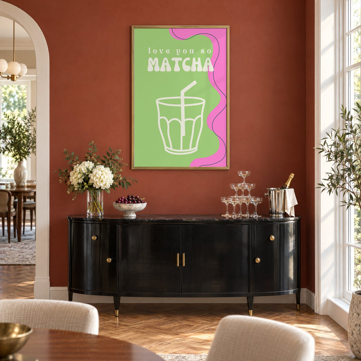 Love you so MATCHA outline glass print in a brass frame on a terracotta wall above a black buffet with a champagne tower