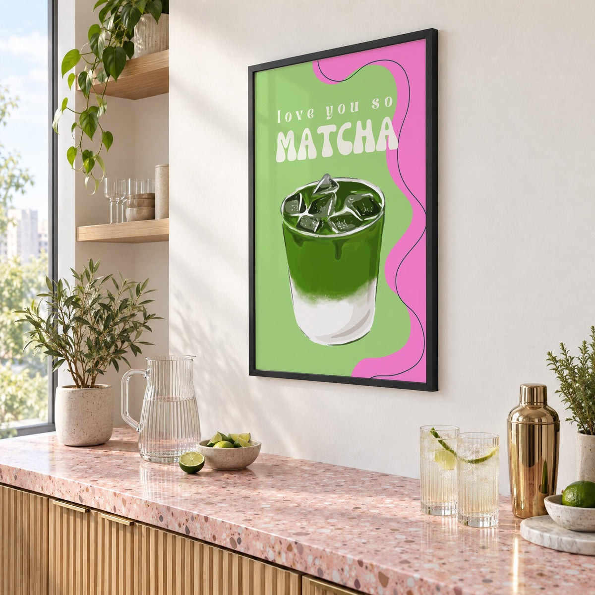 Love you so MATCHA iced latte print in a black frame above a pink terrazzo cocktail counter with limes, seen at an angle