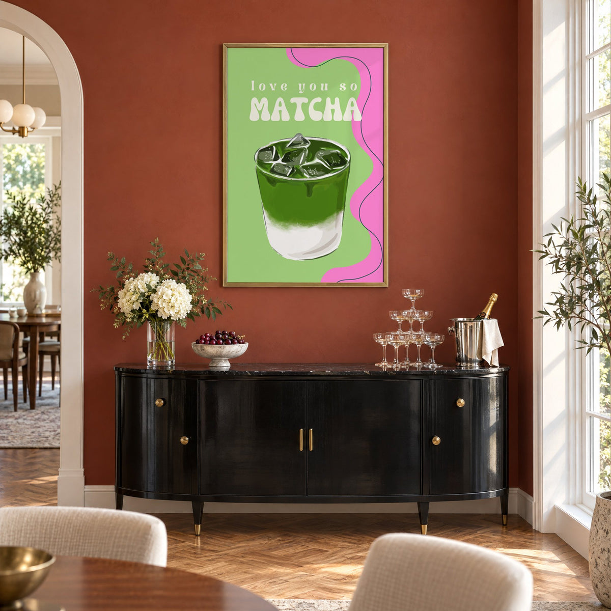 Love you so MATCHA iced latte print in a brass frame on a terracotta wall above a black buffet with a champagne tower