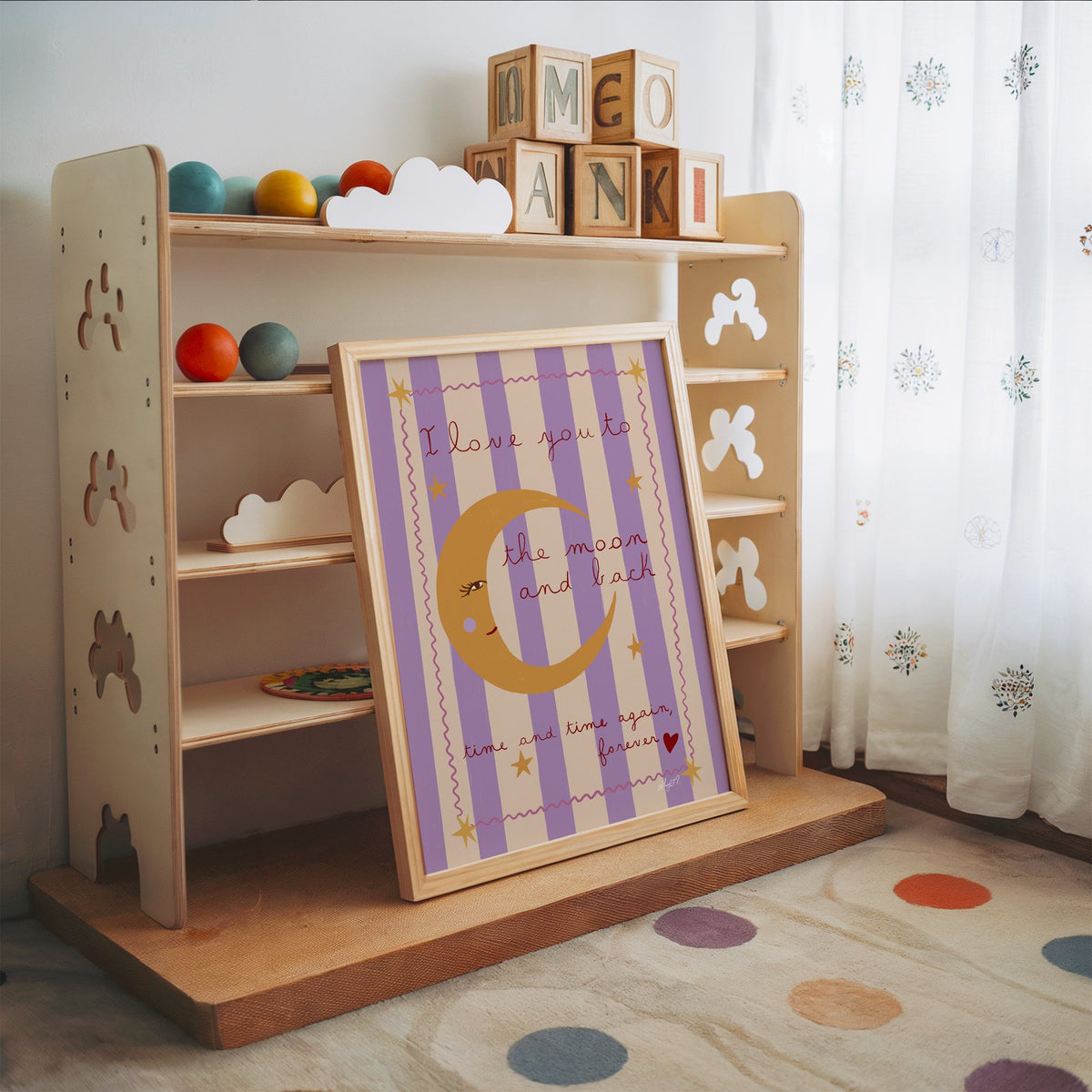 Love you to the moon lilac nursery print in an oak frame leaning on a toy shelf with wooden letter blocks