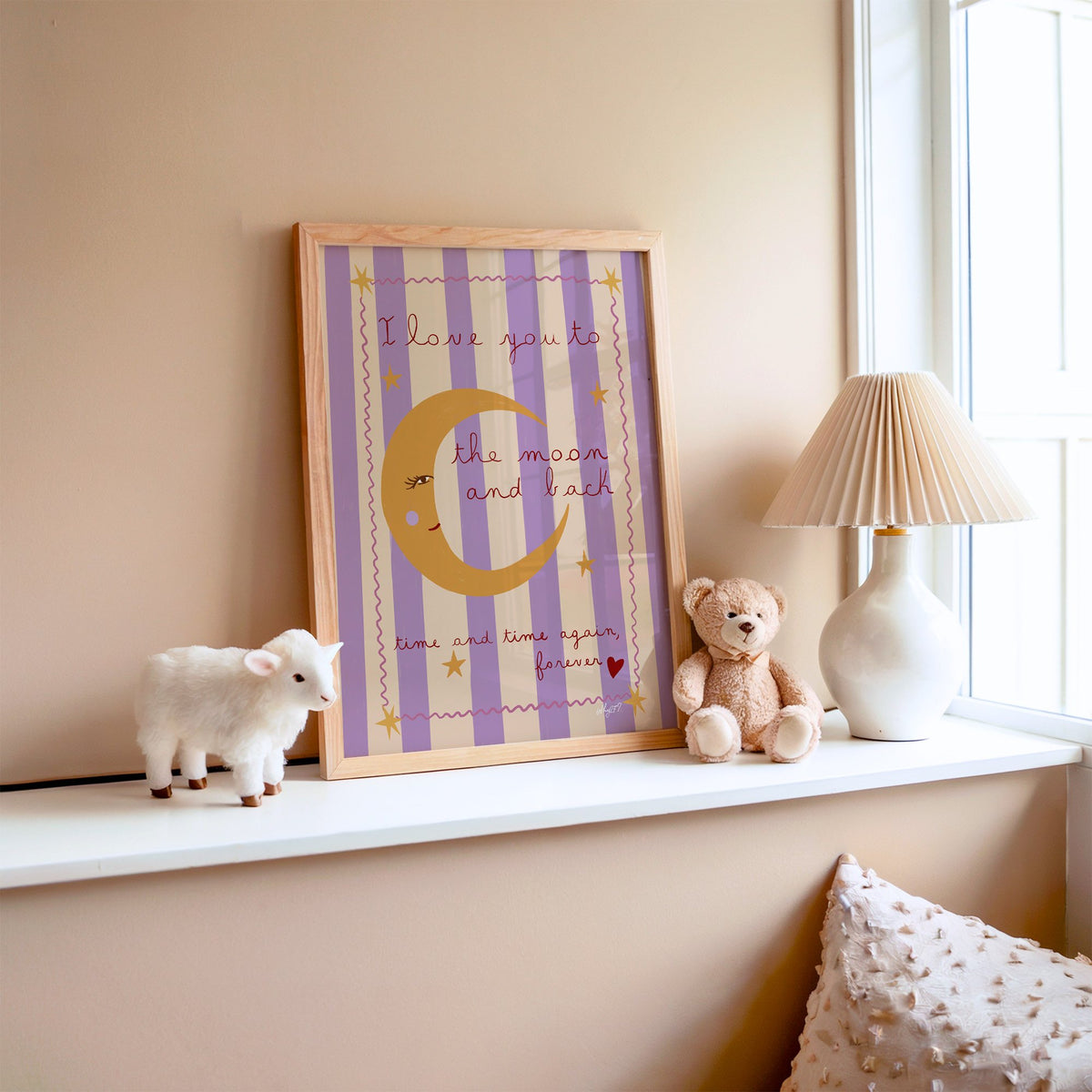 Love you to the moon lilac nursery print in an oak frame on a window ledge with a toy lamb and teddy