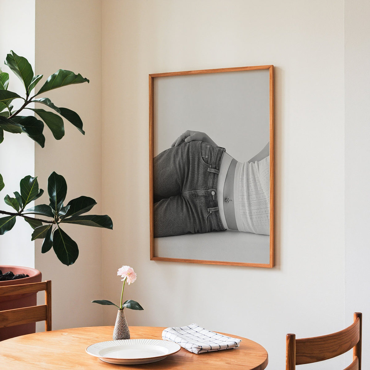 Woman lying in low rise jeans on grey print in a teak frame above a round wooden dining table