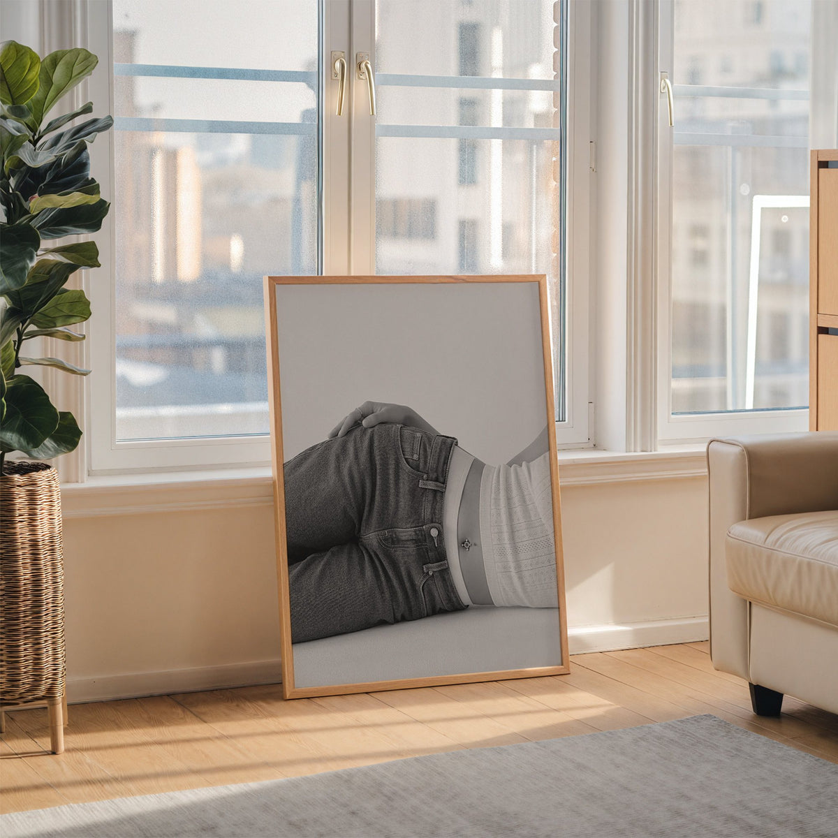 Woman lying in low rise jeans on grey print in an oak frame leaning on the floor beside a fiddle leaf fig