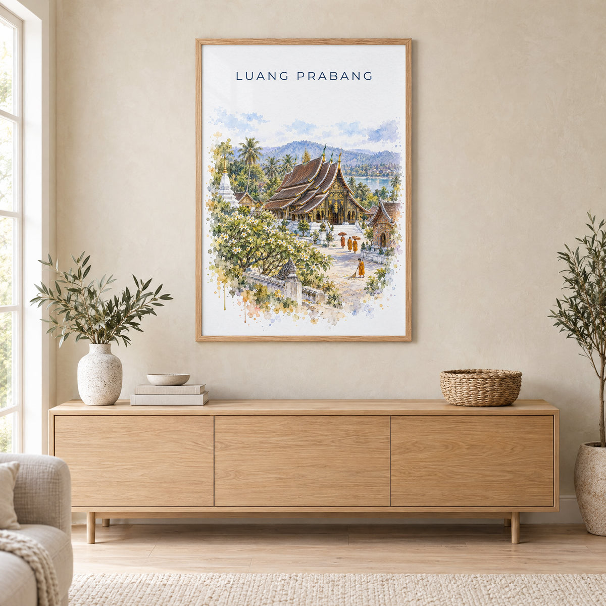 Luang Prabang watercolor print in an oak frame above a light wood sideboard in a Scandinavian living room