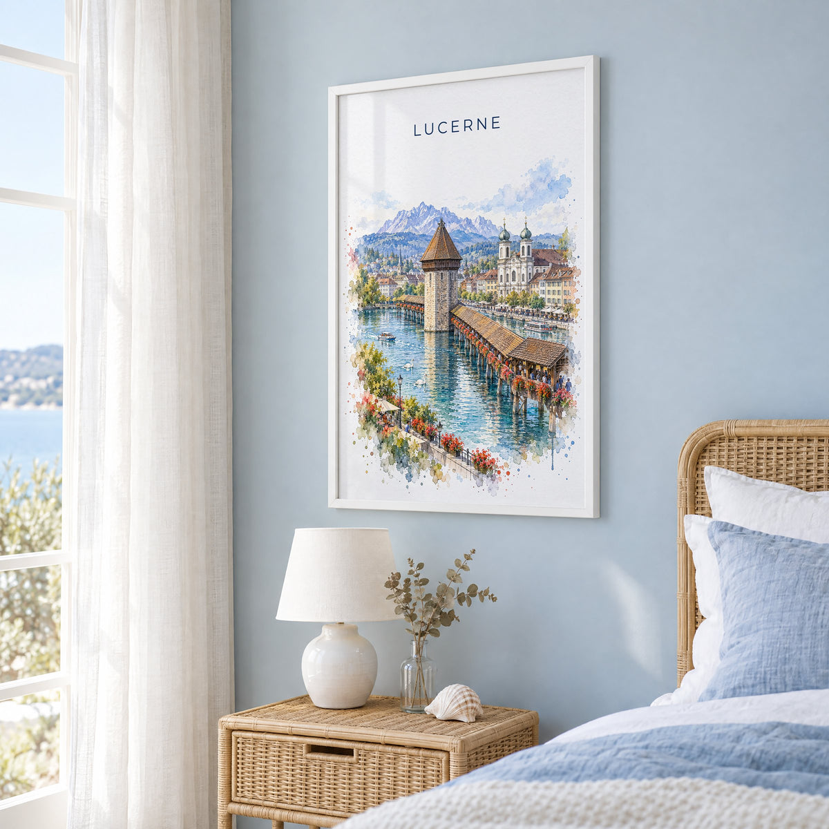 Lucerne watercolor print in a white frame on a pale blue wall beside a rattan bed in a coastal bedroom