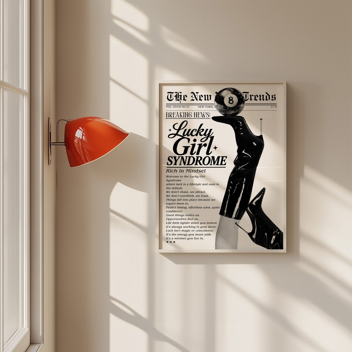 Lucky Girl Syndrome mock newspaper with boots print in a white frame on a sunlit wall beside a red sconce
