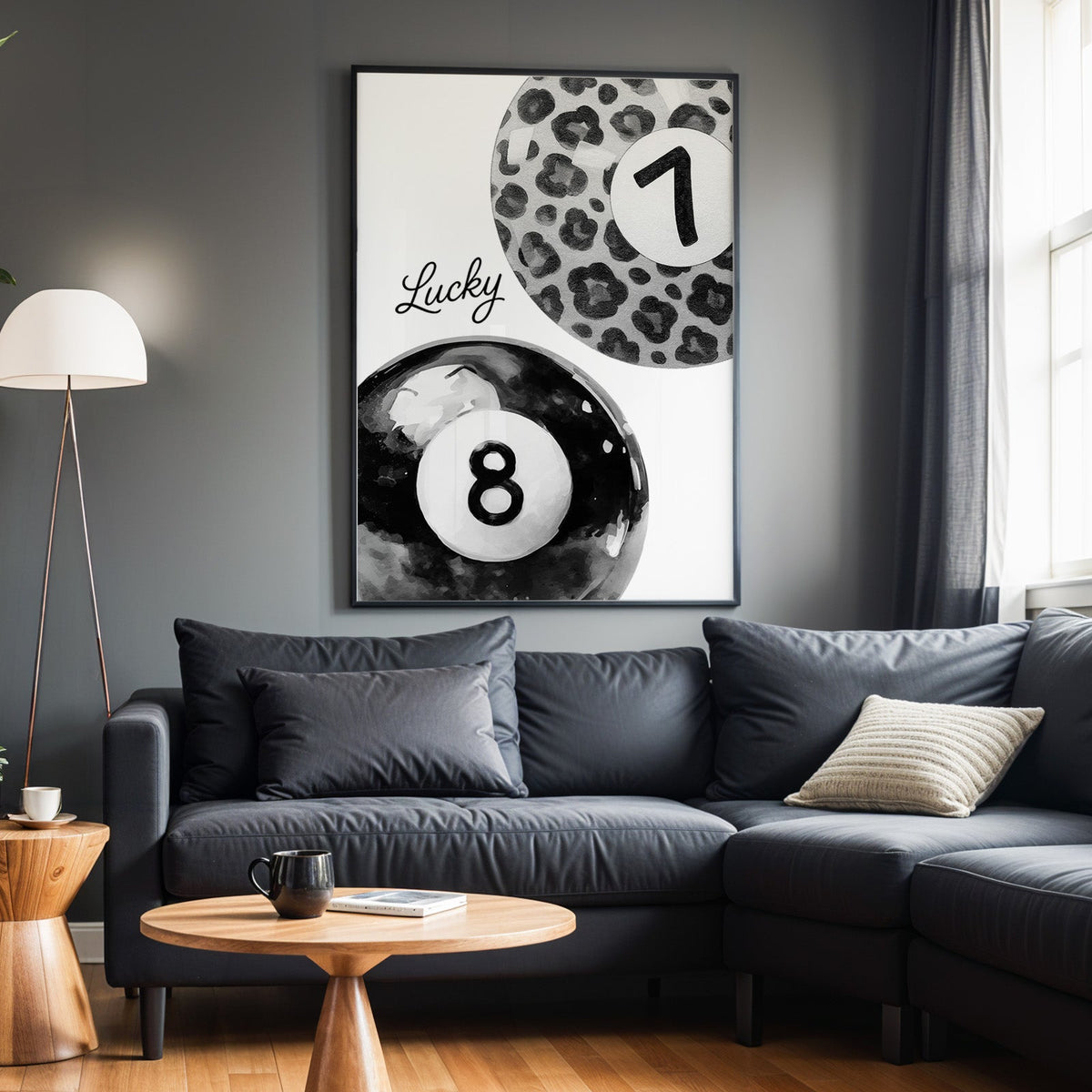 Leopard seven ball and black eight ball watercolor print in a black frame above a charcoal sofa on a grey wall