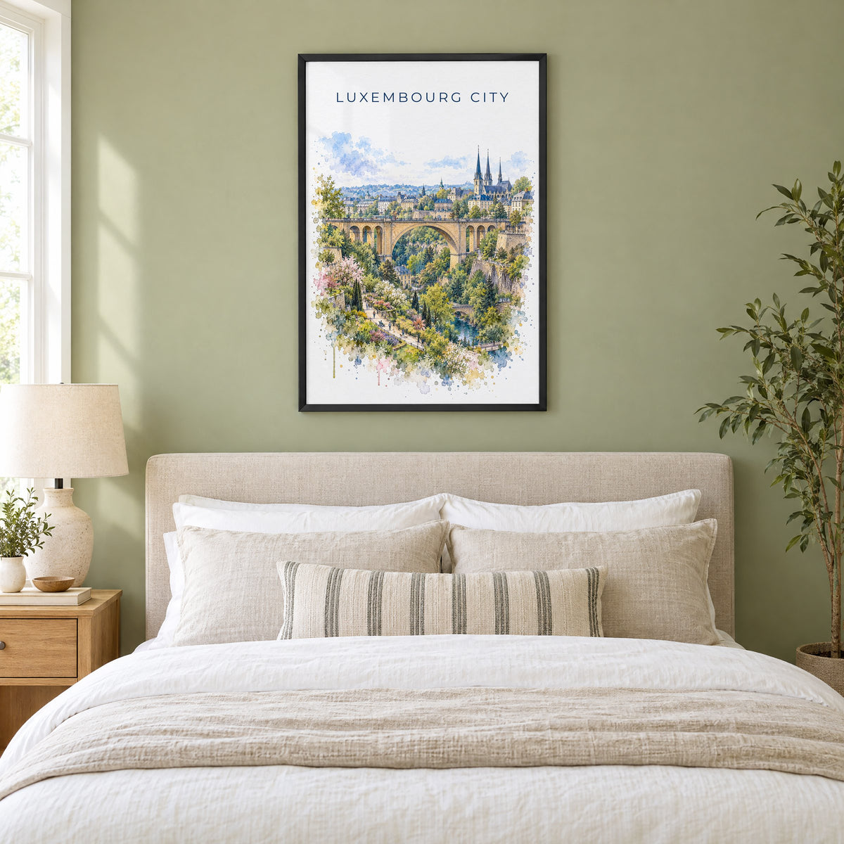 Luxembourg City watercolor print in a black frame above an upholstered headboard in a sage green bedroom