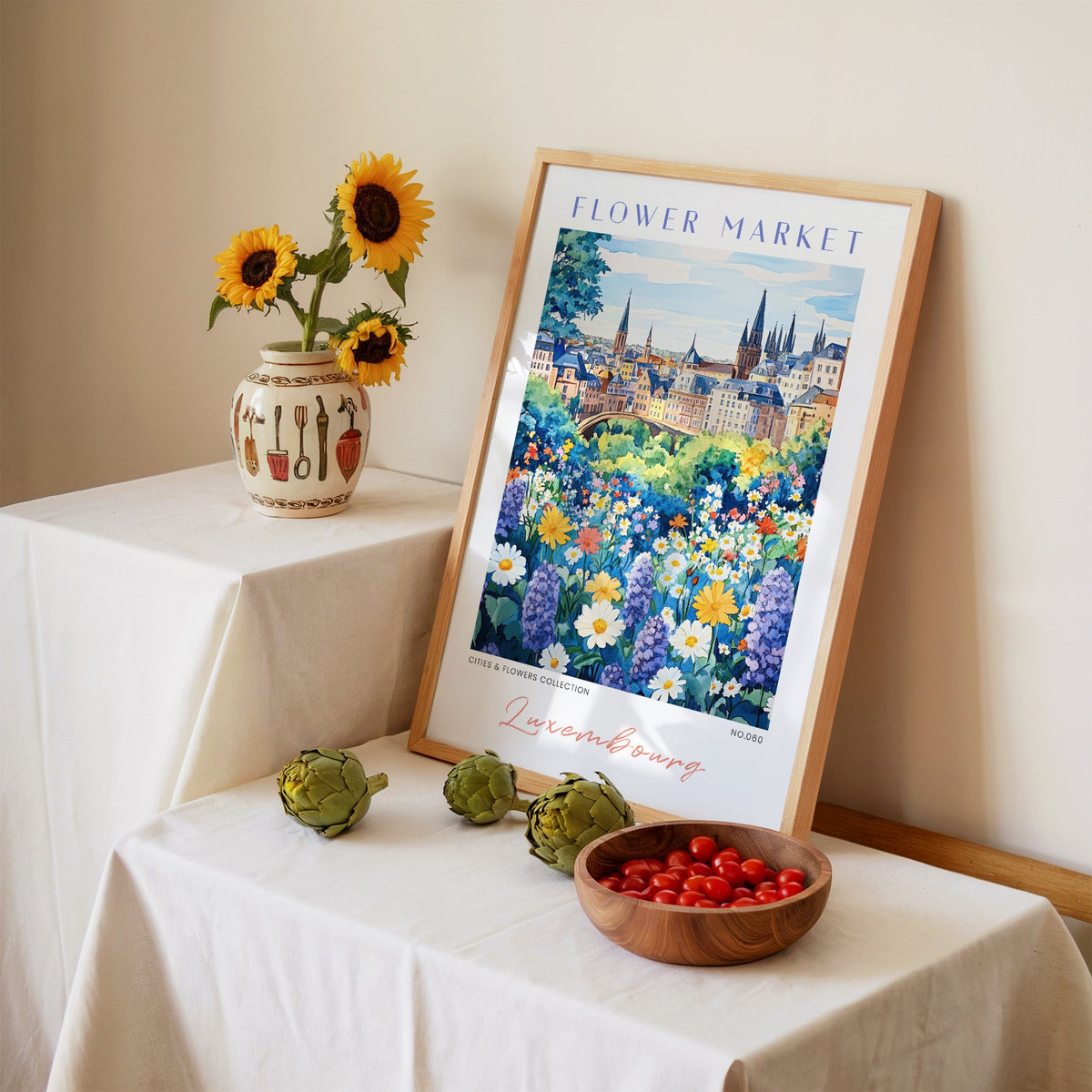 Luxembourg flower market print in an oak frame leaning on a linen-draped table beside a vase of sunflowers