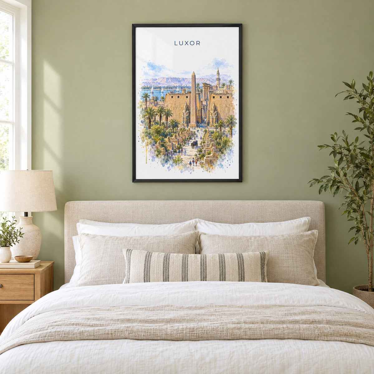 Luxor watercolor print in a black frame above an upholstered headboard in a sage green bedroom