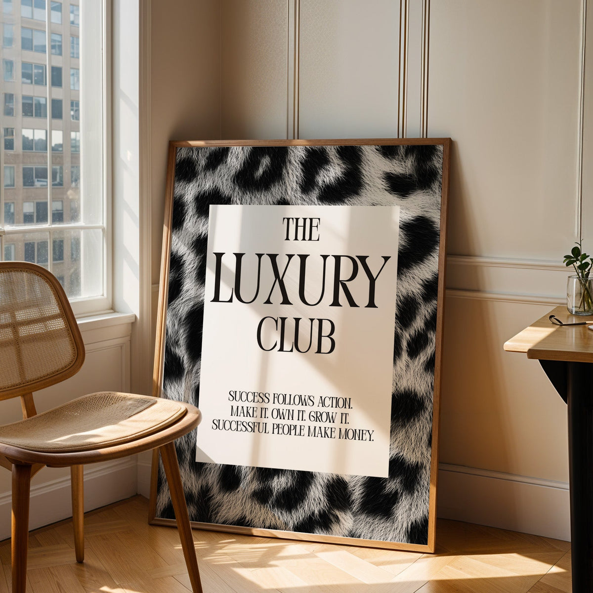 Luxury club serif typography on leopard fur print in an oak frame leaning in a sunlit corner beside a cane chair