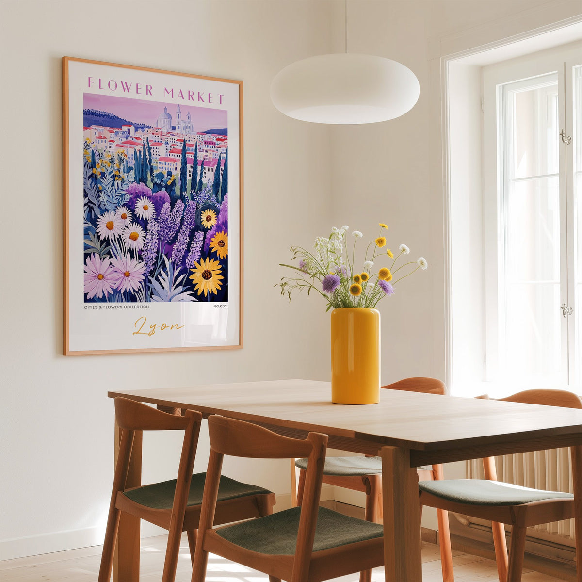 Lyon flower market print in an oak frame above a dining table with a yellow vase and white pendant light