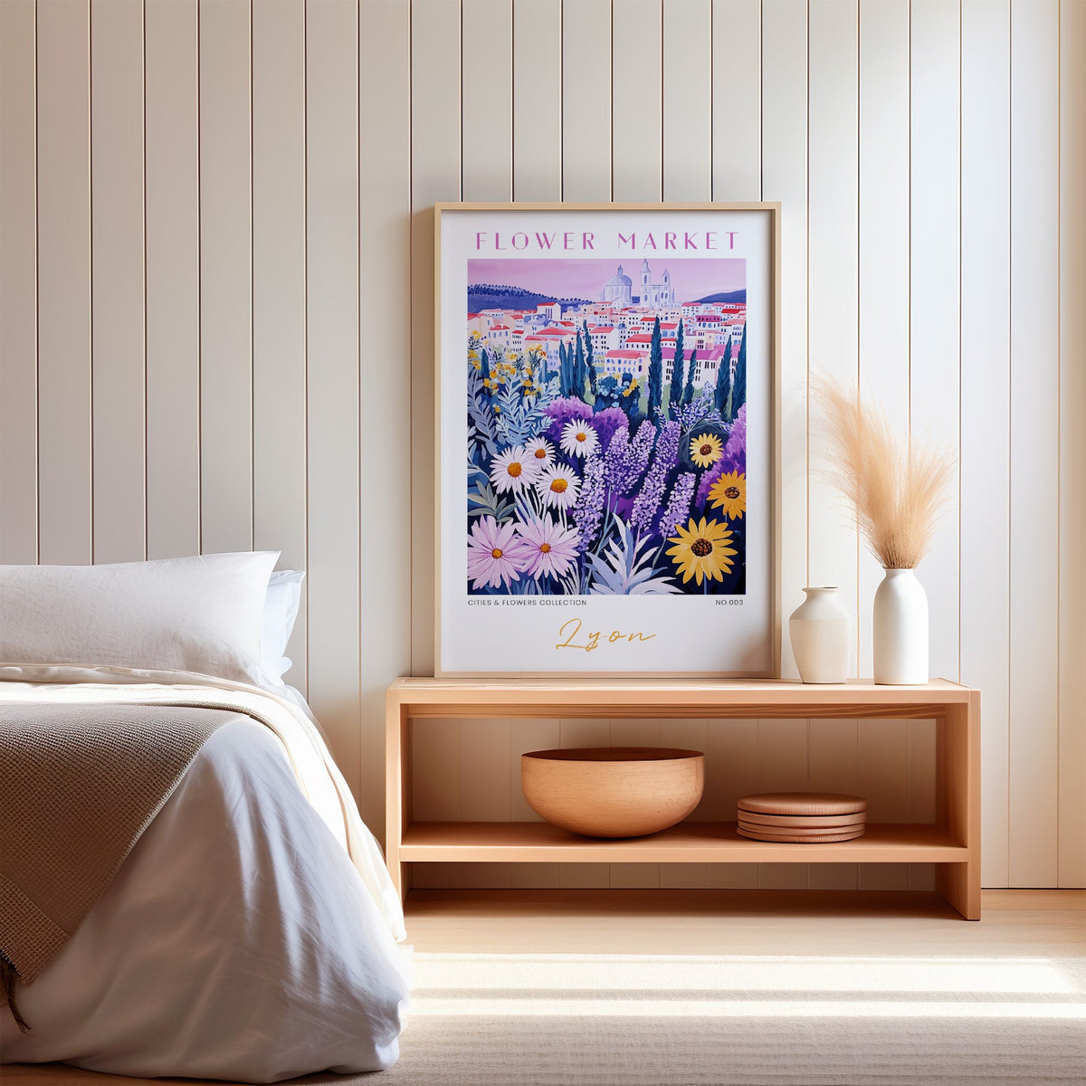 Lyon flower market print in an oak frame on a wood bench against a white shiplap bedroom wall with pampas grass