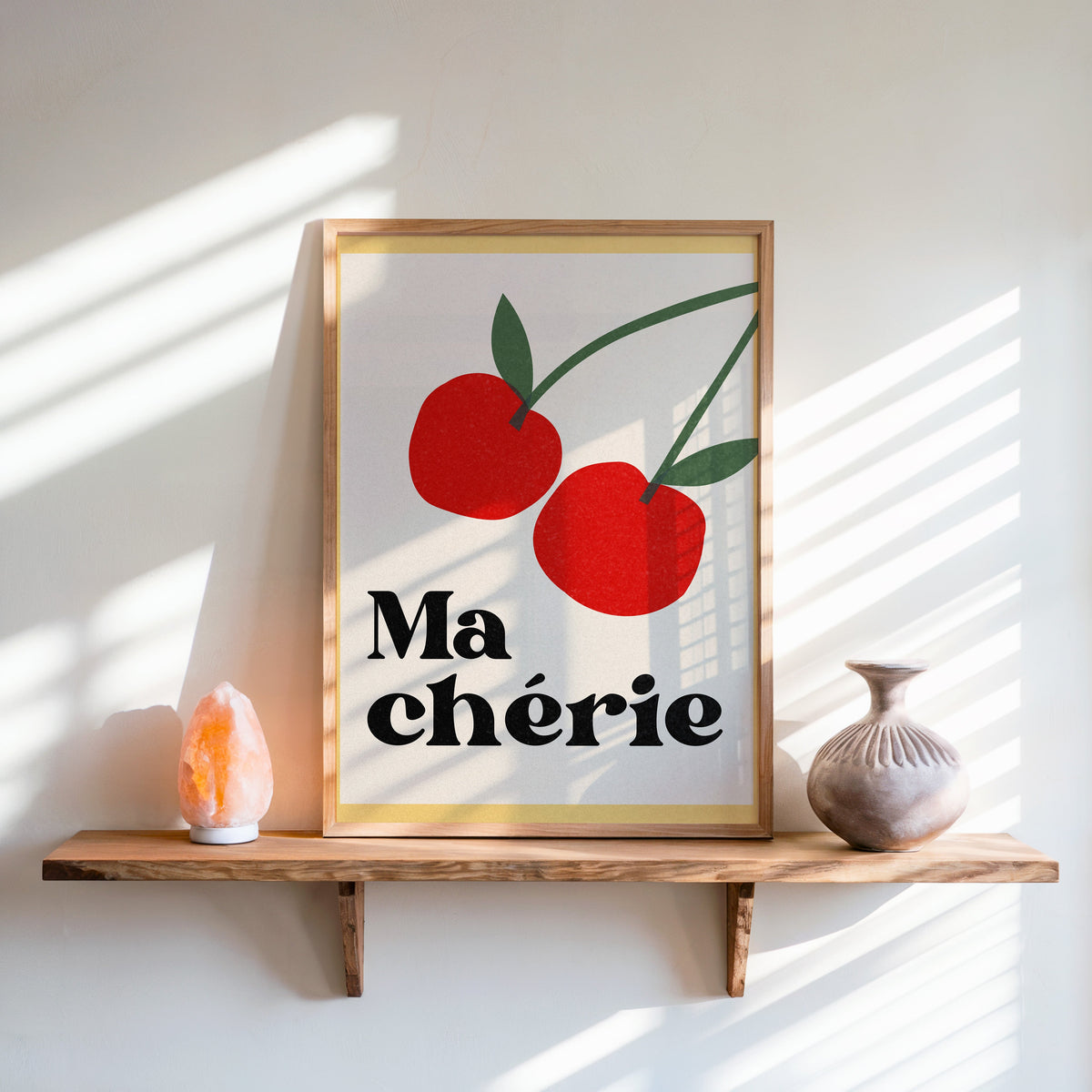 Ma Cherie cherries print in an oak frame on a live-edge shelf beside a salt lamp