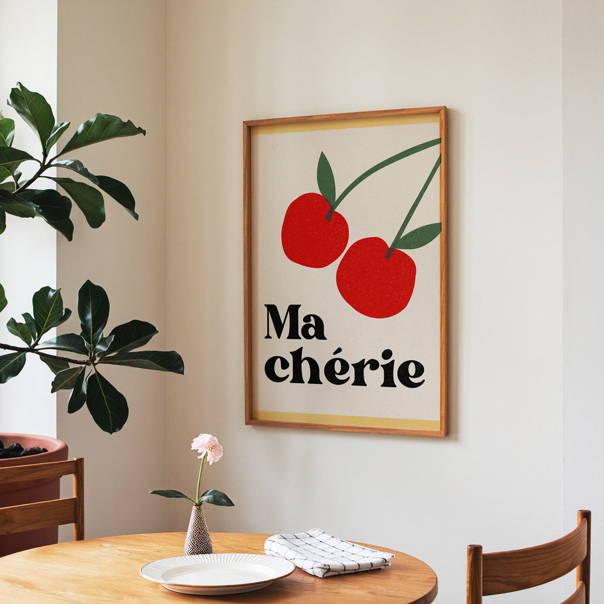 Ma Cherie cherries print in a walnut frame above a round table beside a fiddle-leaf fig
