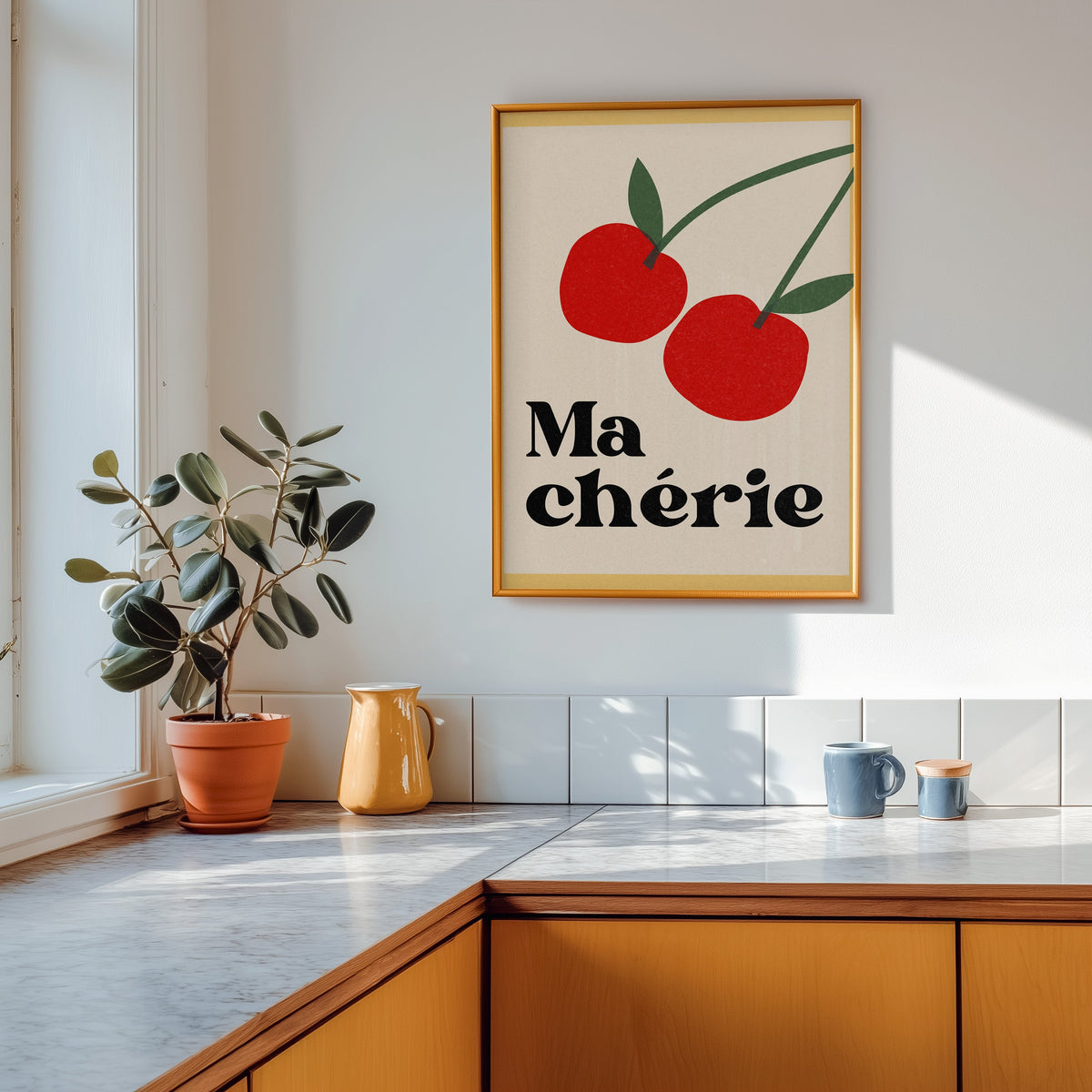 Ma Cherie cherries print shown in a gold frame above a marble counter in a tan kitchen