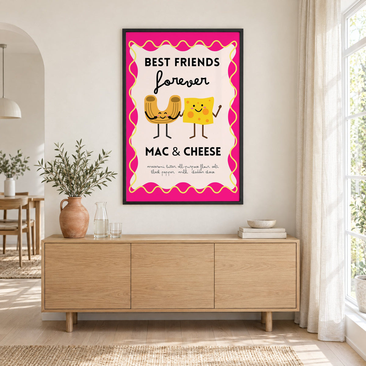 Mac and cheese best friends pink print in a black frame above an oak sideboard with a terracotta vase of olive branches