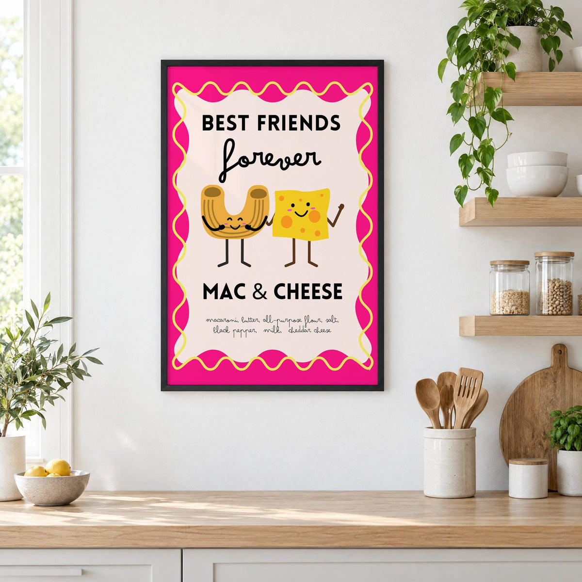 Mac and cheese best friends pink print in a black frame in a white kitchen beside open wood shelves and glass jars