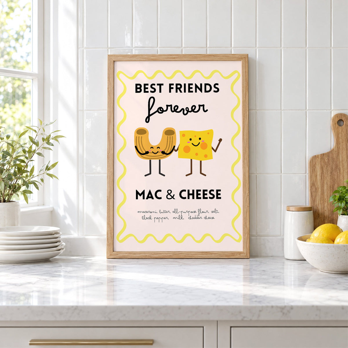 Mac and cheese best friends yellow print in an oak frame leaning on a marble counter by white tiles and lemons