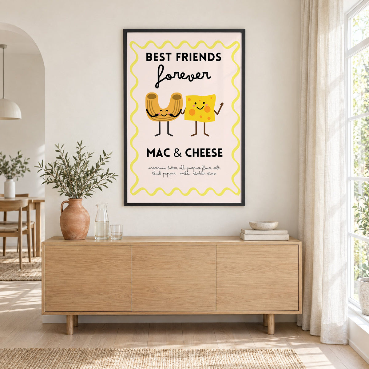 Mac and cheese best friends yellow print in a black frame above an oak sideboard with a terracotta vase of olive branches