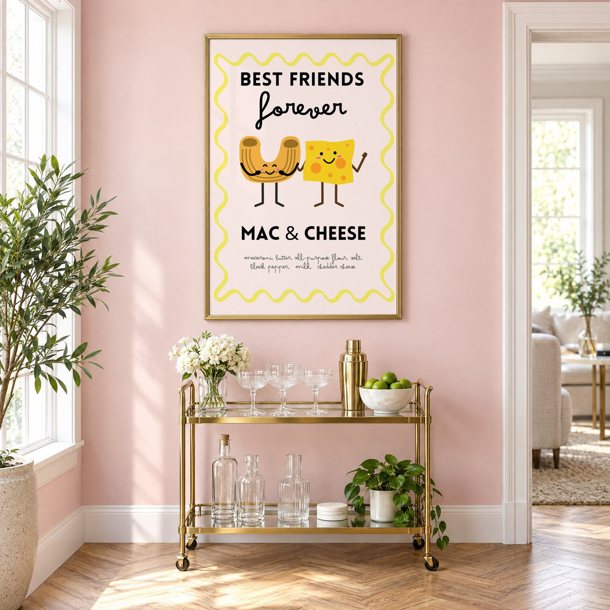 Mac and cheese best friends yellow print in a brass frame above a gold bar cart on a blush pink wall