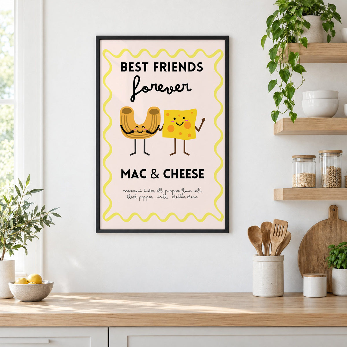 Mac and cheese best friends yellow print in a black frame in a white kitchen beside open wood shelves and glass jars