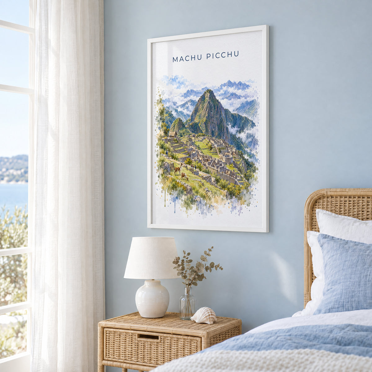 Machu Picchu watercolor print in a white frame on a pale blue wall beside a rattan bed in a coastal bedroom