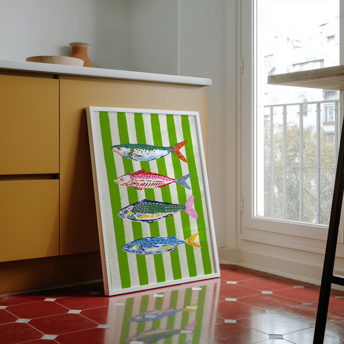 Mackerel row print in a white frame against yellow cabinets on a red tiled floor