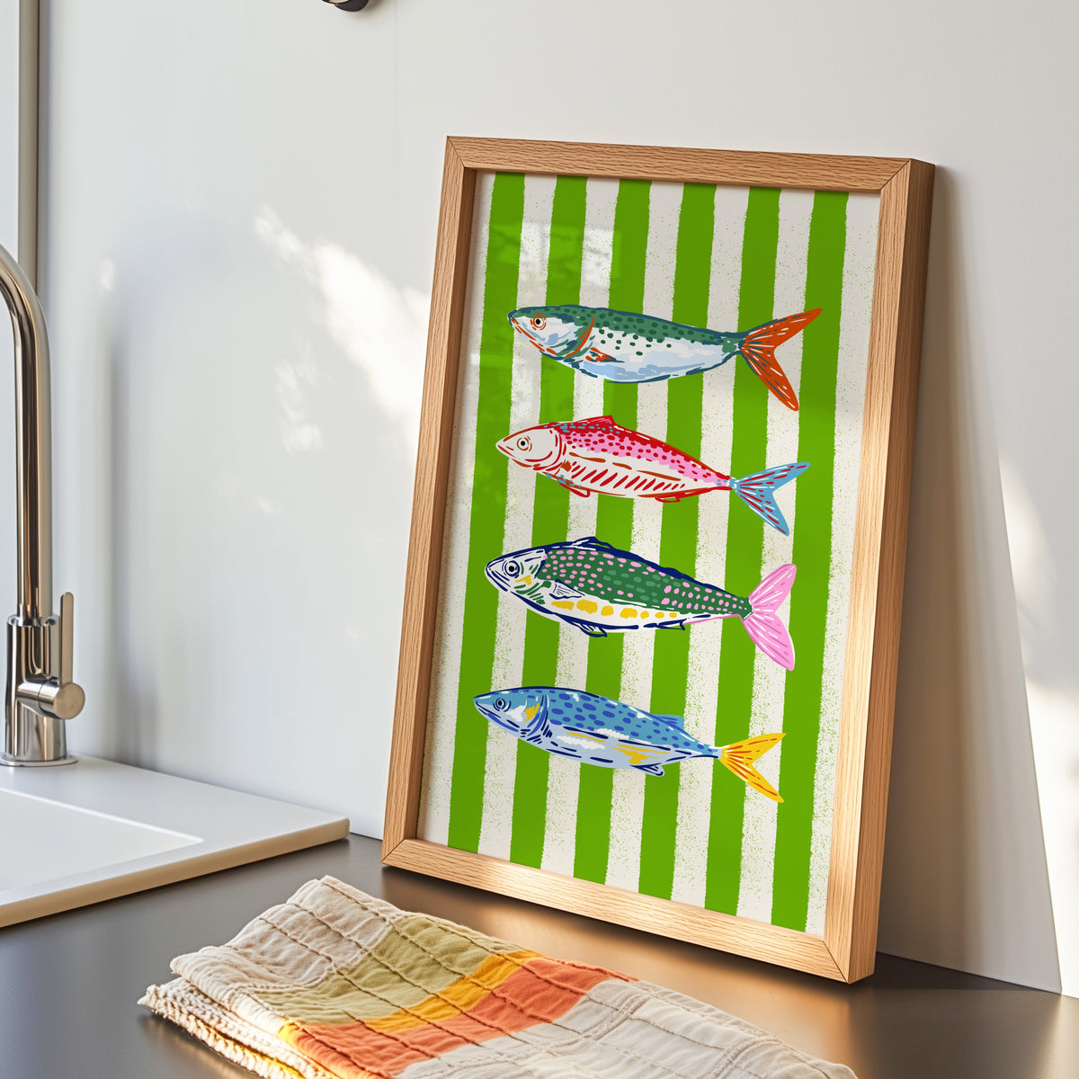 Mackerel row print in an oak frame by the kitchen sink beside a striped tea towel