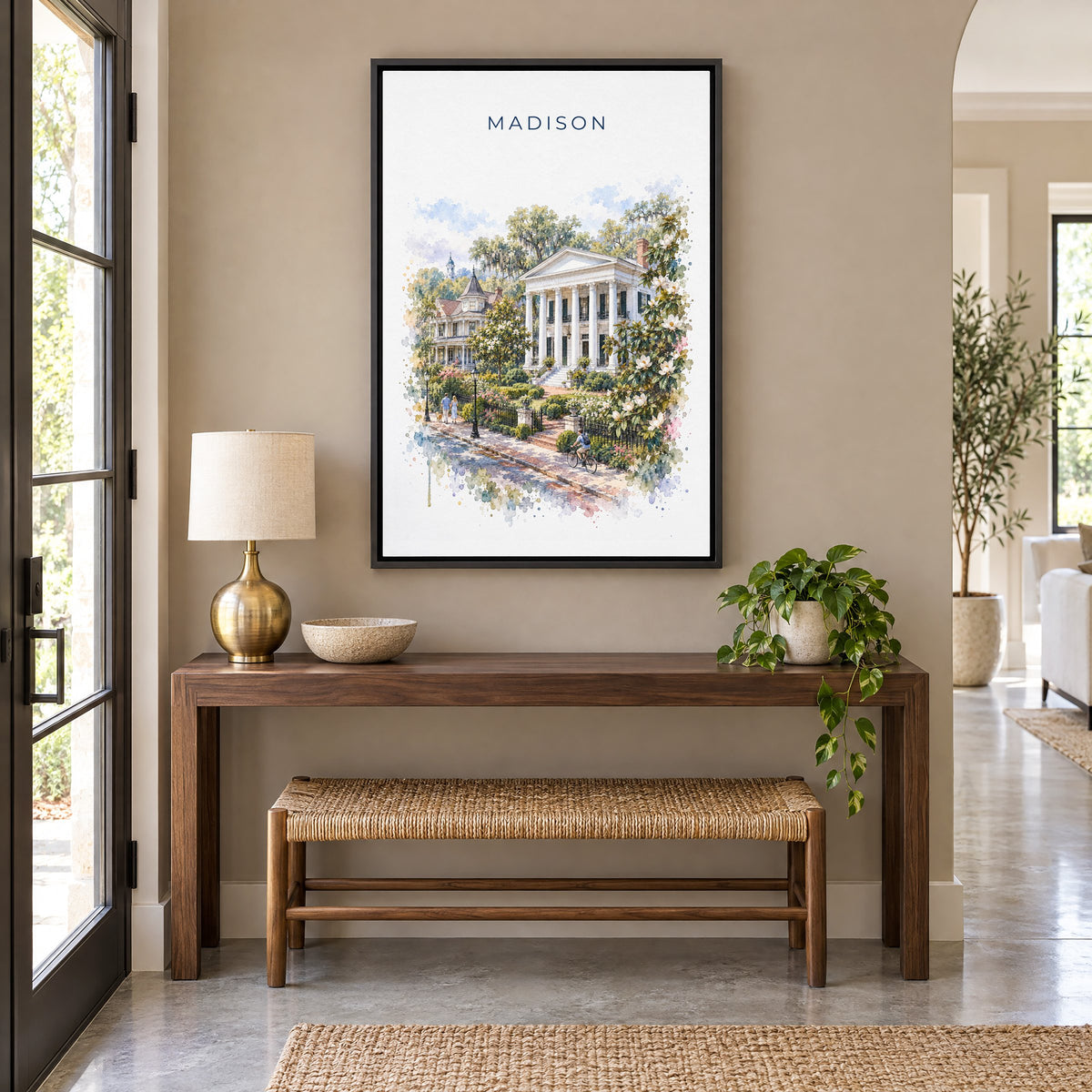 Madison, Georgia watercolor print as a black floater canvas above a walnut console and woven bench in an entryway