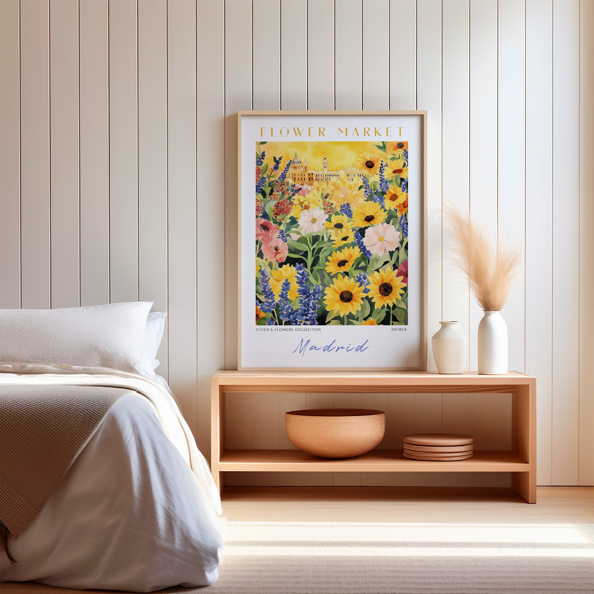 Madrid flower market print in an oak frame on a wood bench against a white shiplap bedroom wall with pampas grass