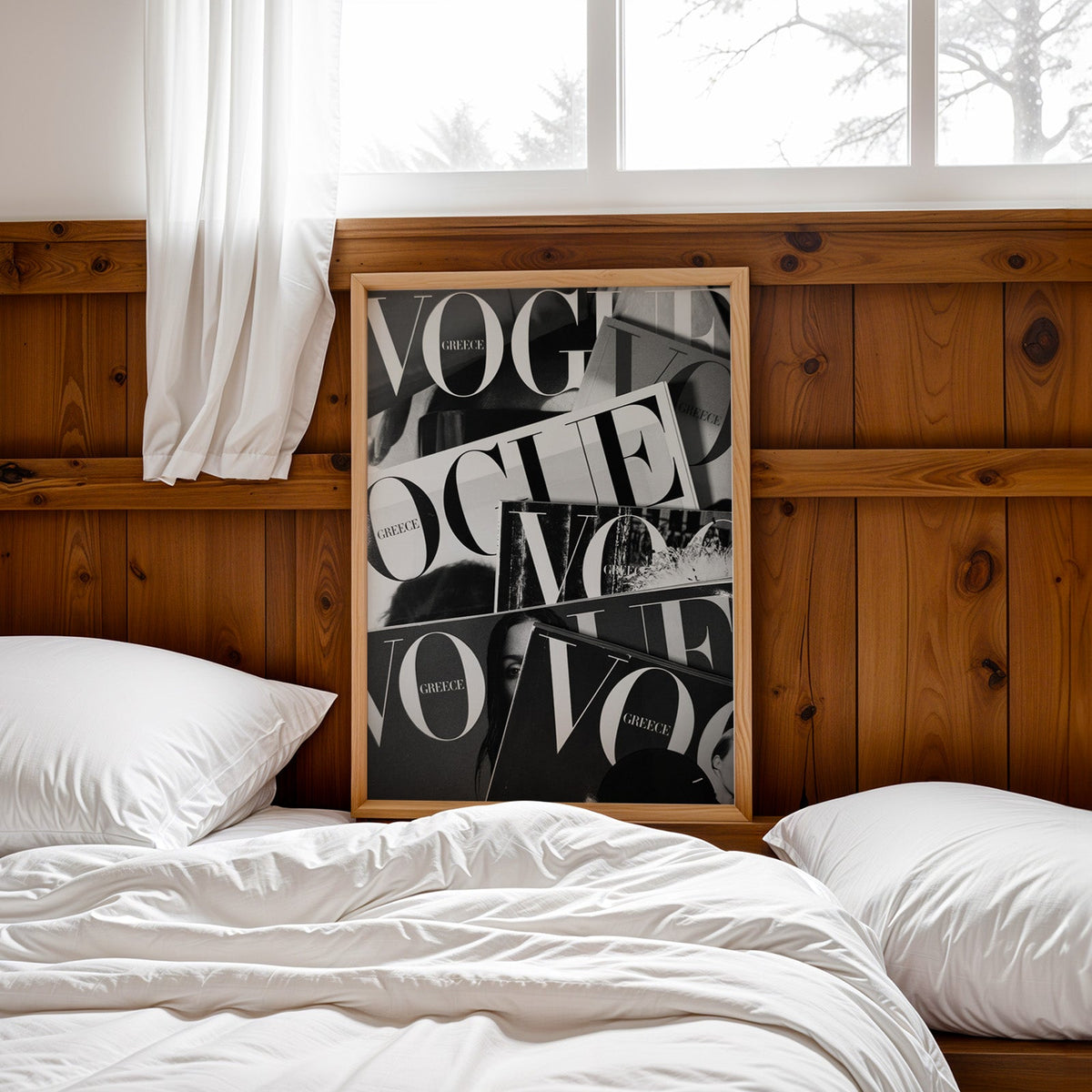 Overlapping magazine covers with giant lettering print in a pine frame leaning on a wood headboard over white bedding