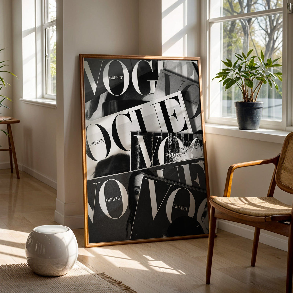Overlapping magazine covers with giant lettering print in a walnut frame on a wood floor beside a cane chair and sunny window