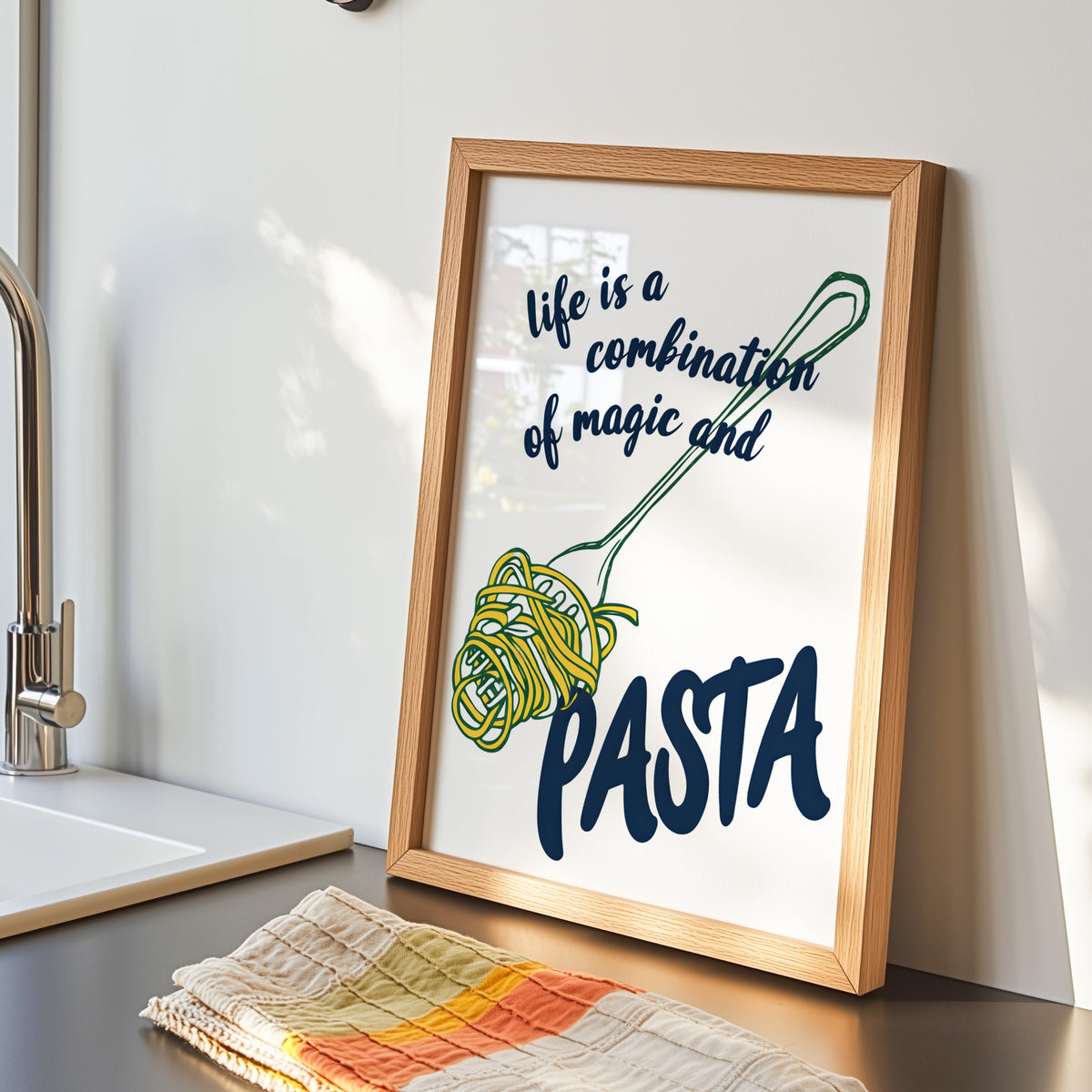 Magic and Pasta print in an oak frame by the kitchen sink beside a striped tea towel