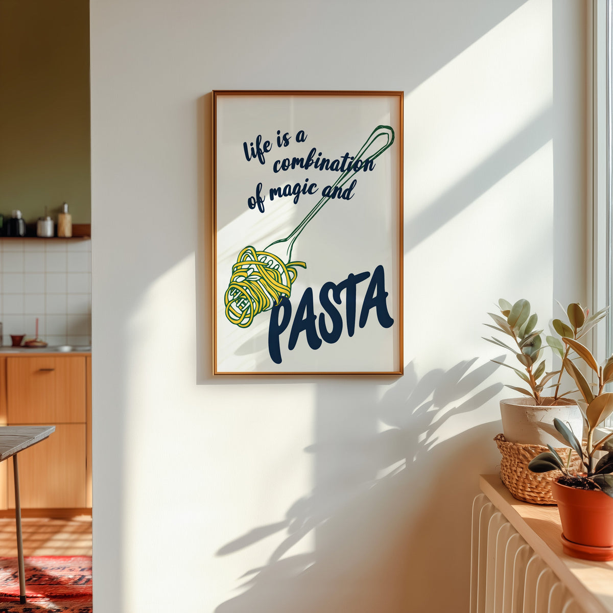 Magic and Pasta print shown in a gold frame in sunlight with plants and a kitchen beyond