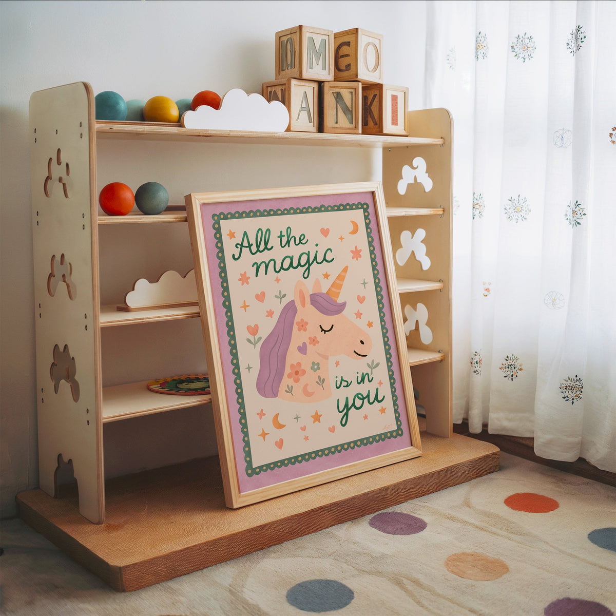 Magic is in you unicorn nursery print in an oak frame leaning on a toy shelf with wooden letter blocks