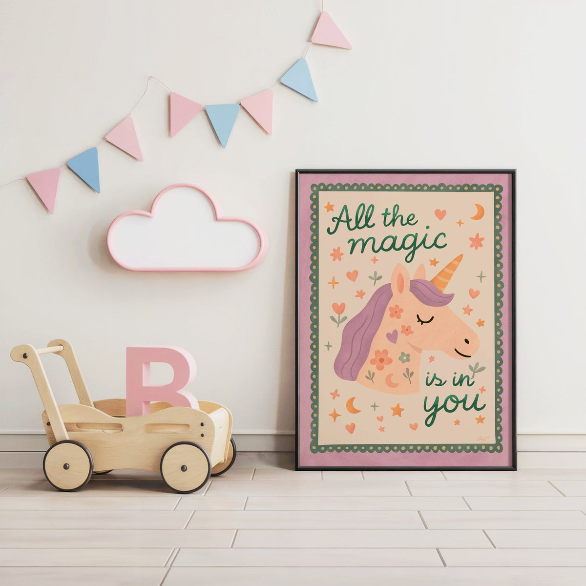 Magic is in you unicorn nursery print in a black frame under pastel bunting by a wooden baby walker